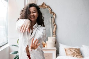 Happy woman in a white shirt enjoying a relaxing morning indoors with a smile.