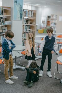 Children in a school library depicting a bullying scene, highlighting anti-bullying awareness.